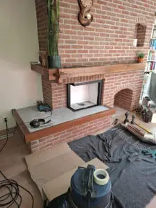 Open haard renovatie met de lijst van de nieuwe inzethaard met isolatiewol in de bestaande haard opening