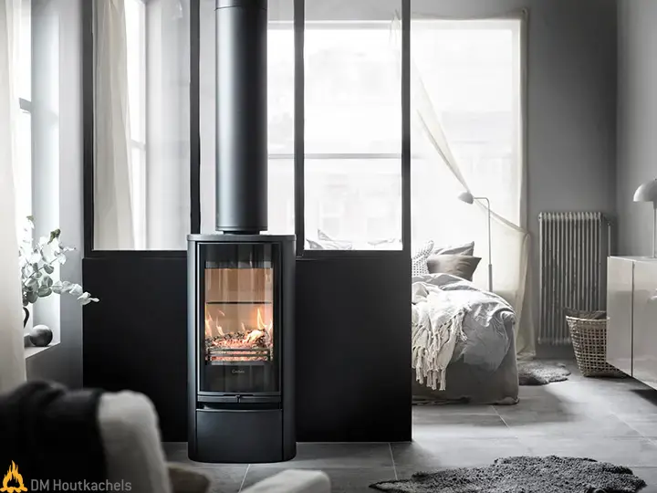 De compacte Contura 810G Style houtkachel brandt sfeervol in een moderne woonkamer met grote ramen, zwarte afwerking en strak Scandinavisch design.