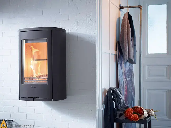 De zwarte Contura 810W Style hangt strak aan een witte bakstenen muur en toont een helder vlammenspel naast een lichte moderne hal met kapstok.