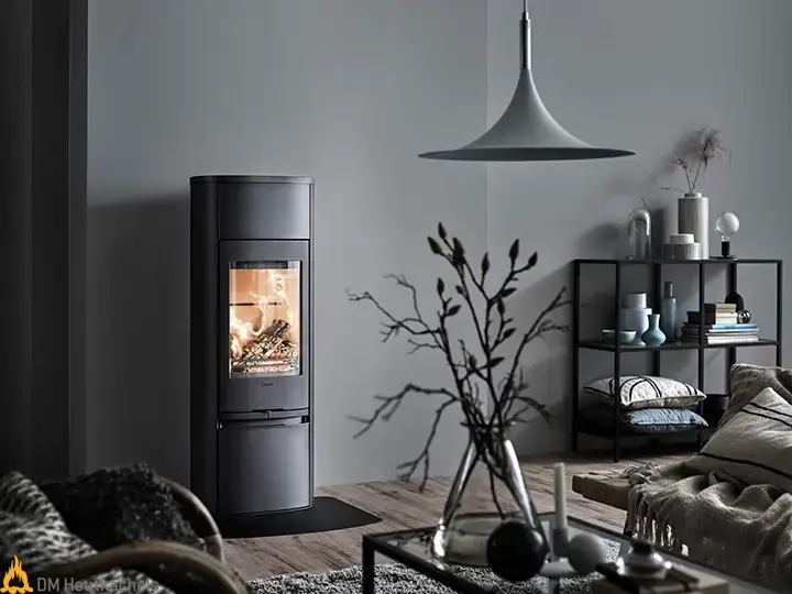In een rustige woonkamer brandt de Contura 890 Style houtkachel, met compacte zwarte afwerking, naast een houten vloer en minimalistische inrichting.