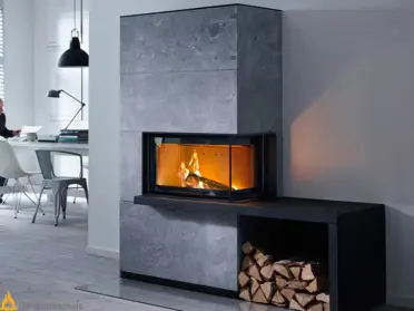 De Contura i41T in grijs speksteen brandt warm in een moderne woonkamer met open haardvak en gestapeld hout naast een lichte eethoek.