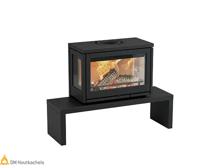 Zwarte Contura i8 MyCube B houtkachel van staal met panoramisch vuurzicht, geplaatst op een minimalistische bankconstructie in een modern interieur.