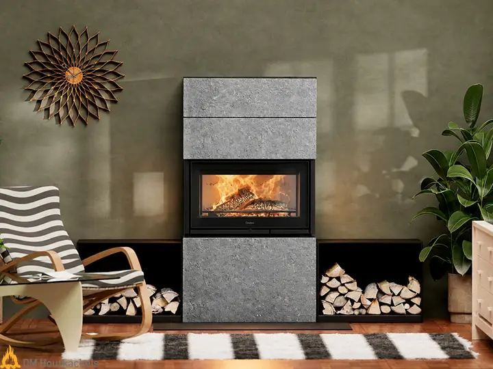 Een Contura i8 MyCube TG met speksteen omlijsting toont een levendig vuur achter glas, naast stapels haardhout in een modern interieur.