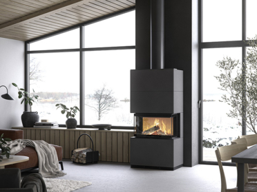 De Contura i51AA houtkachel brandt warm in een moderne woonkamer met grote ramen, zwart wandpaneel en uitzicht op een besneeuwd landschap.
