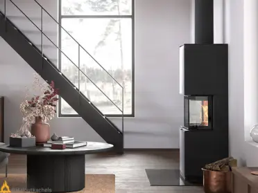 In een lichte woonkamer staat de Contura i61 zwart staal naast een trap, met zichtbaar vuur in de kachel en een strakke, moderne afwerking.