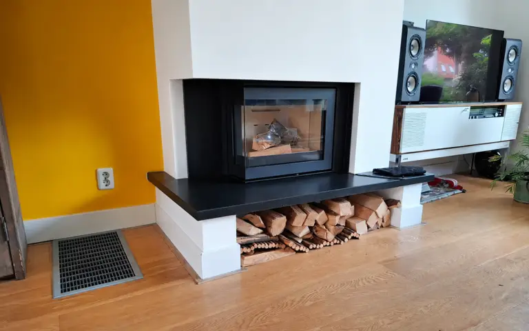 Moderne inzethaard met houtblokken in een woonkamer met houten vloer en vloerverwarming als basiswarmte