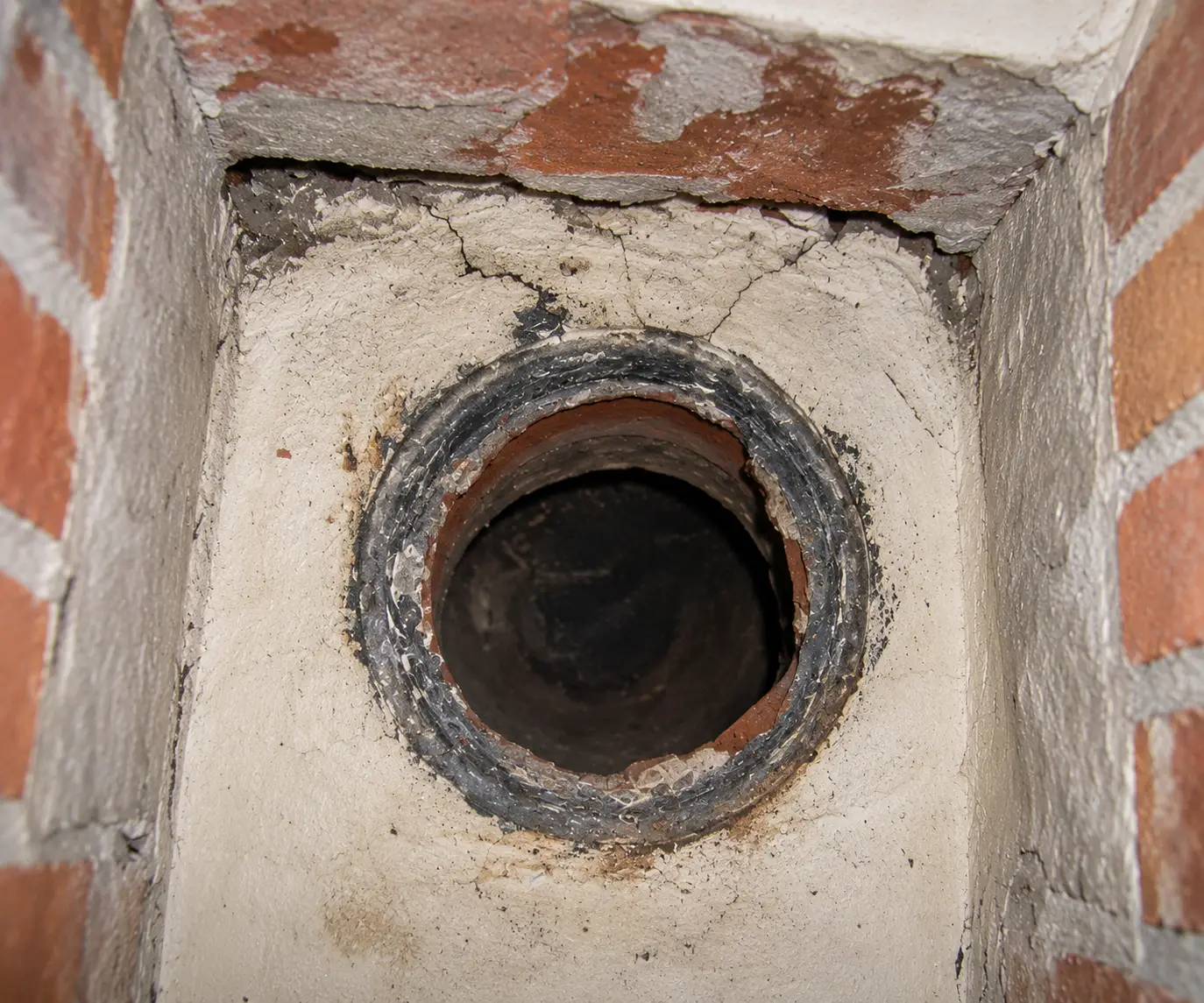 Moderne houtkachel aangesloten op een bestaande gemetselde schoorsteen in een lichte woonkamer.